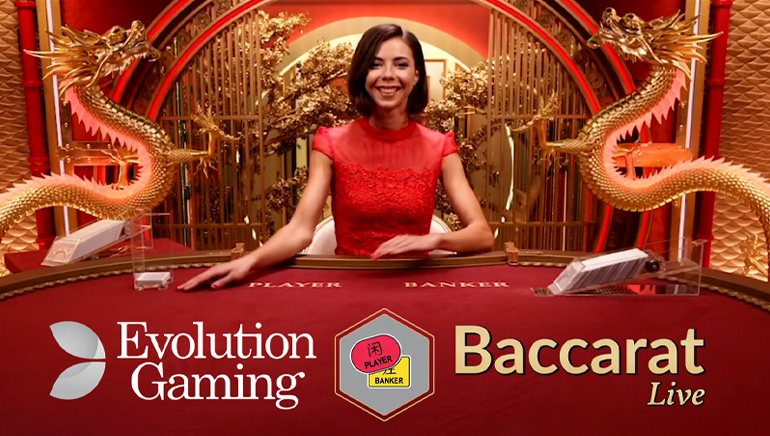 Evolution Gaming živi krupije sjedi za crvenim i zlatnim baccarat stolom